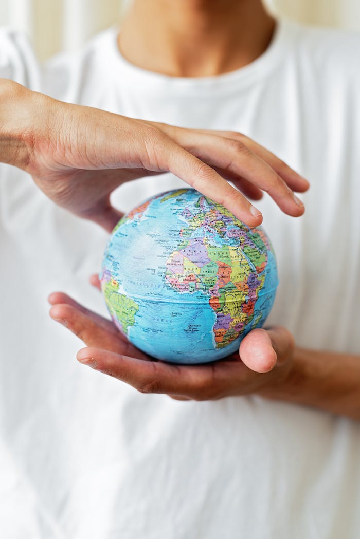 about-img Close-up of hands holding a world globe symbolizing global unity and environmental care.