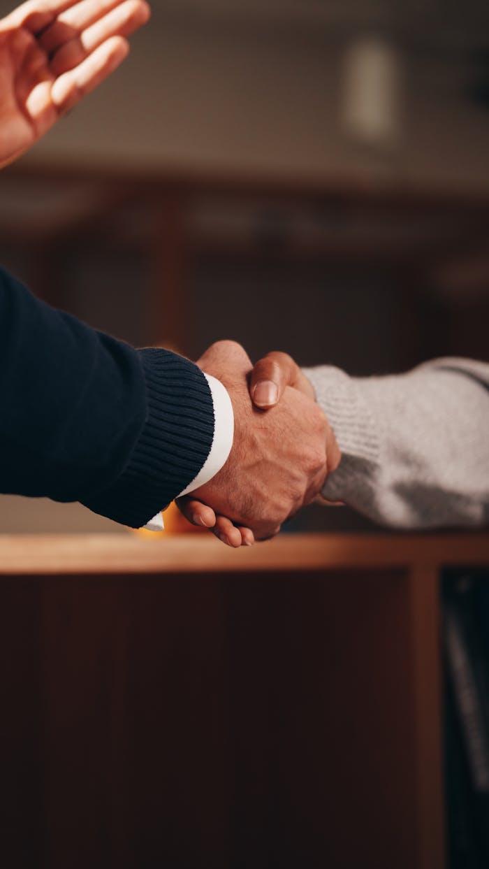 about-02 Two hands shaking in a professional setting, symbolizing business deal or agreement.