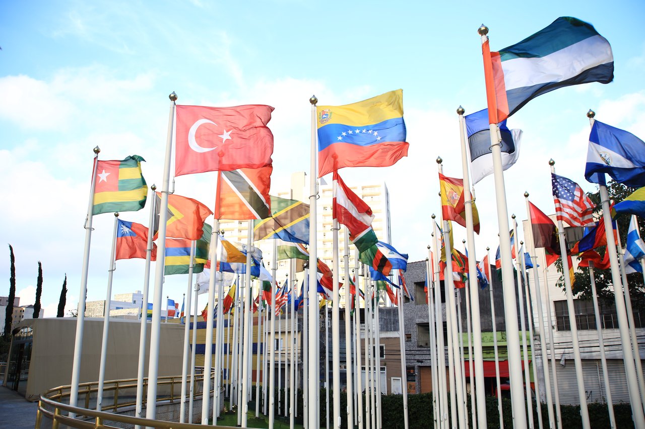 hero-img-01 A vibrant collection of international flags in a cityscape setting, symbolizing global unity.